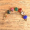 A 14k yellow gold link bracelet featuring 7 carved oval gemstone scarab beetles on a wooden background.