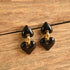 Heart-shaped earrings with black hearts and gold accents on a wooden surface