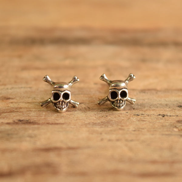 silver skull earrings on wood background