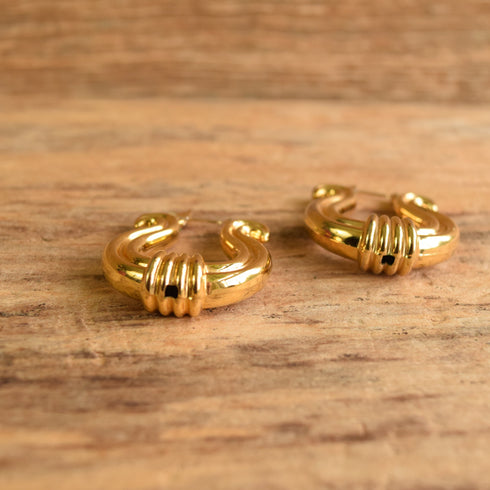 Gold hoop earrings on a wooden surface