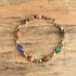 Gold filled bracelet featuring 8 gemstones carved into scarab beetles on a wooden background.