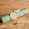 Gabrielle Gould Silver Bird Brooch leanding on a gemstone rod on a wooden background