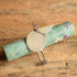 Gabrielle Gould Silver Bird Brooch leanding on a gemstone rod on a wooden background