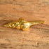 A vintage gold toned spiral seashell brooch on a wooden background